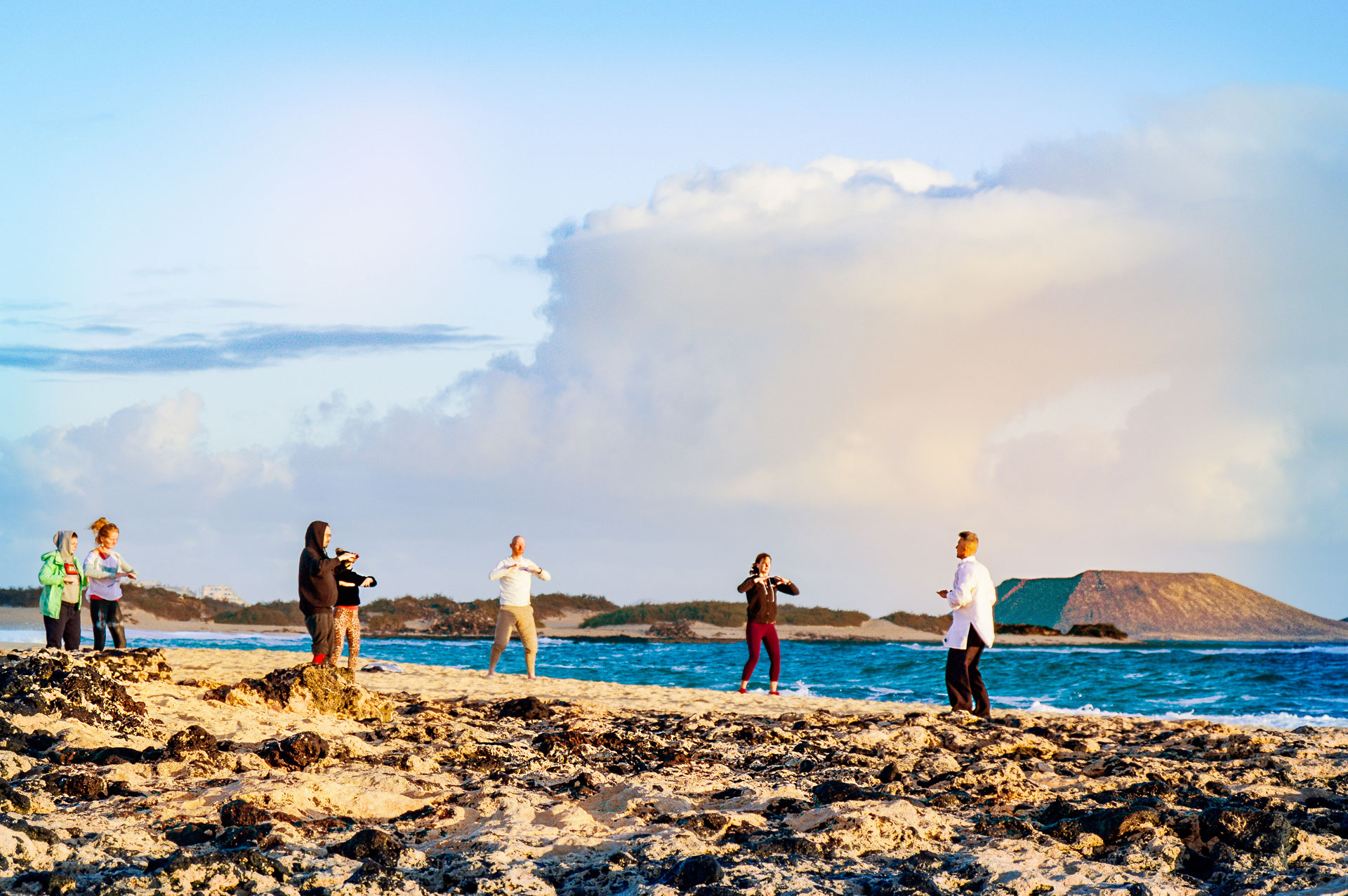 Qigong teacher leading a class for six participants on a beach in Fuerteventura