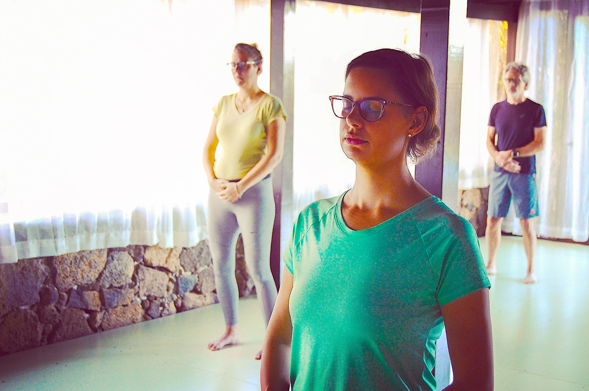 Three people practising standing Qigong meditation in the yoga shala at Villa Azul, Fuerteventura