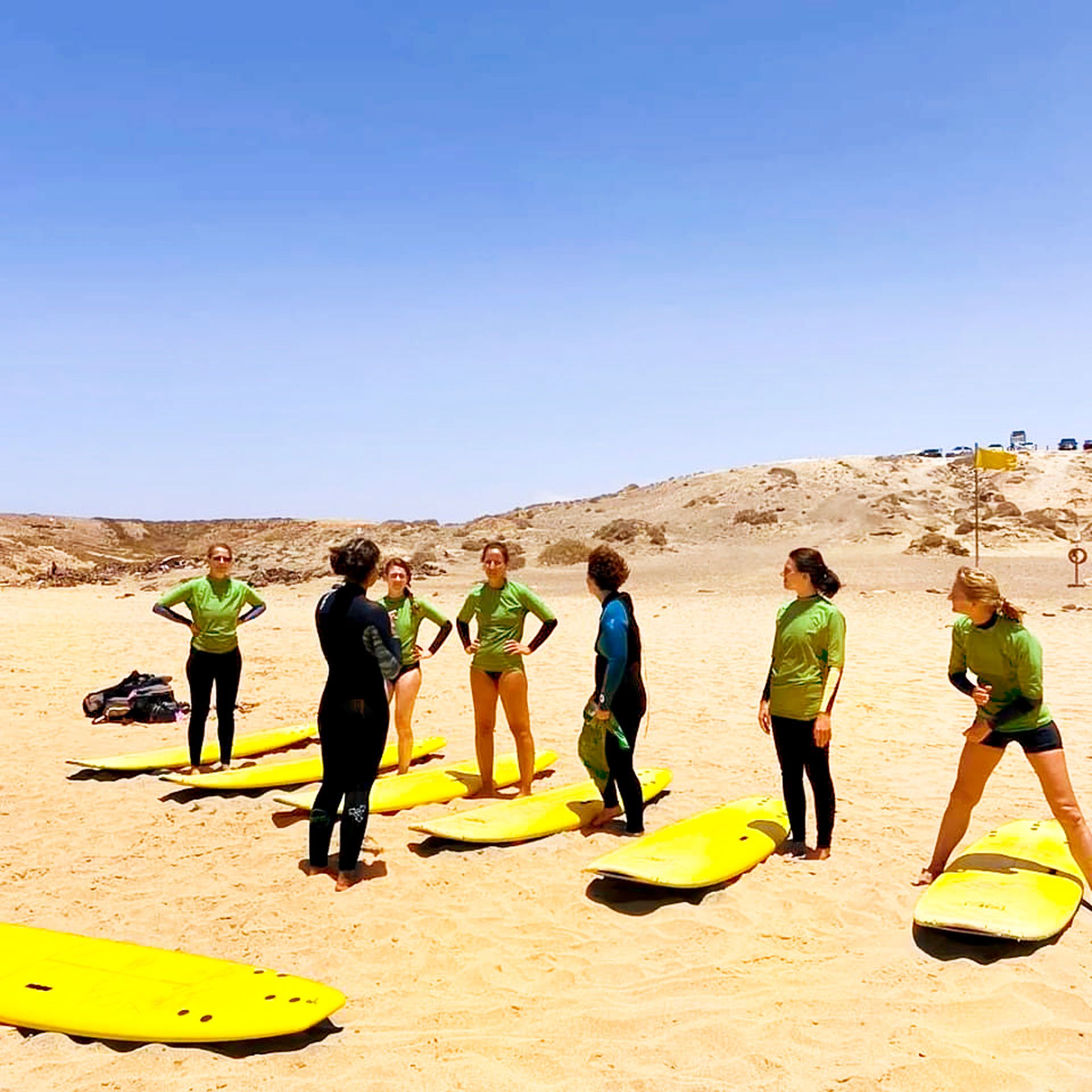 Six women taking a surf lesson on a sunny beach in Fuerteventura