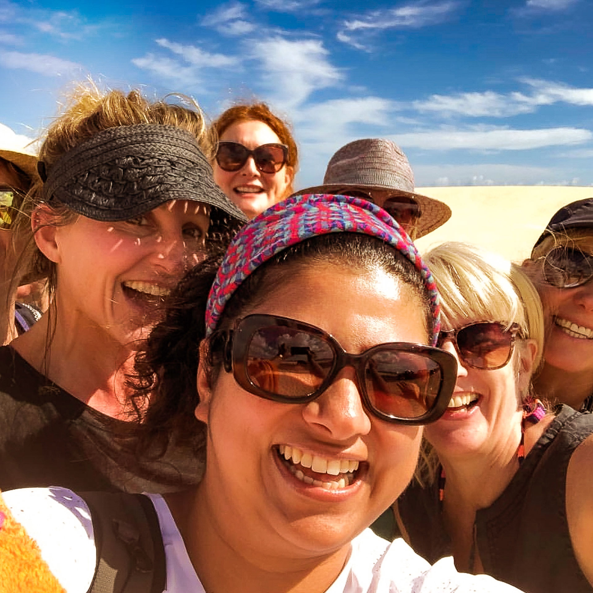 Seven women smiling and laughing together during an excursion in the Corralejo dunes, Fuerteventura