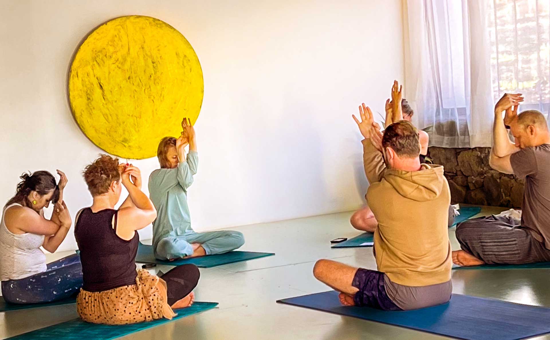 Yoga teacher and five students practising seated Eagle Pose in the yoga shala at Villa Azul, Fuerteventura