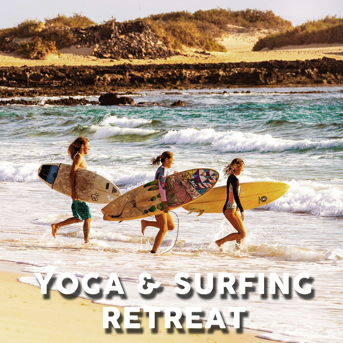 yoga-surfing-retreat-fuerteventura Three young women with surfboards walking towards the sea on a beach in Fuerteventura
